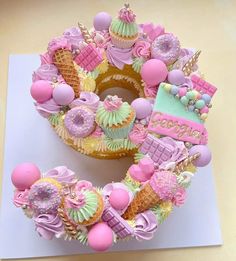 a birthday cake decorated with pink, green and yellow icing on top of a table