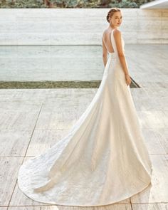 a woman in a white wedding dress standing on the ground with her back to the camera