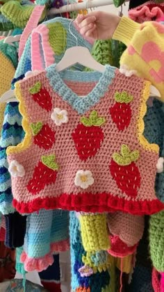 a child's sweater is hanging on a rack with other knitted clothing items