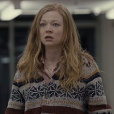 a woman with long red hair wearing a sweater