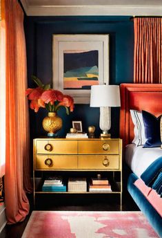 a bedroom with blue walls, gold furniture and red curtains on the window sill