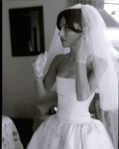 a woman in a wedding dress is holding her veil over her head