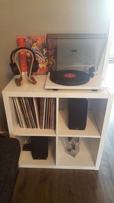 a record player sitting on top of a white shelf filled with vinyl records and cds