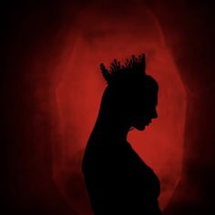 the silhouette of a woman with a crown on her head, against a red background