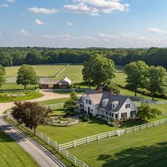 an aerial view of a large white farm house surrounded by lush green fields and trees