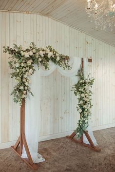 the wedding arch is decorated with white flowers and greenery for an elegant touch to the venue