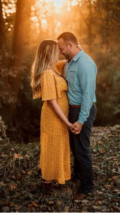 a man and woman kissing in the woods at sunset with sunbeams behind them