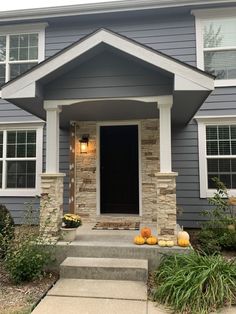 a gray house with pumpkins on the front steps