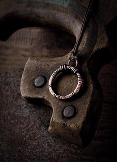 -------  This solid copper ring is hand-forged. Small circles and notches reminiscent of prehistoric finds are worked into the surface. These small marks vary slightly on each pendant and make it unique. To give the piece more depth, it is given an antique patina. The handmade eyelet is soldered firmly so that the pendant remains stable in the future.  -------  The pendant is 28 mm wide and 39 mm high with the eyelet & comes with a brown cotton ribbon. -------  The shape of the circle represents Small Ornaments, Cotton Ribbon, Copper Ring, Rustic Jewelry, Copper Pendant, Copper Rings, Copper Pendants, Lucky Charm, Hand Forged