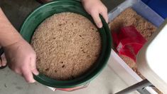 a person holding a green bowl filled with dirt