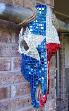 a red, white and blue cow skull hanging on a brick wall