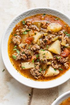 a white bowl filled with meat and vegetable soup