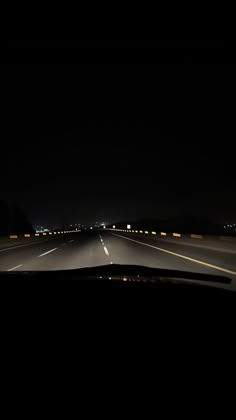 an empty highway at night with the lights on