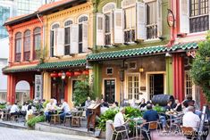 people sitting at tables in front of colorful buildings