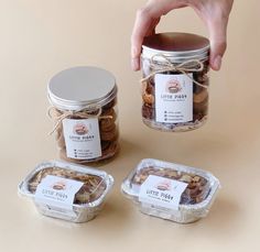 a person holding a jar with cookies in it and three other containers next to it