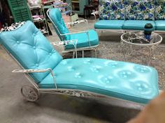 a blue chaise lounge chair sitting on top of a rug next to a glass table