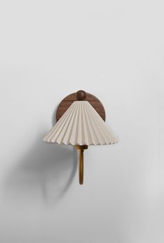 a wall lamp with a wooden base and white shell shade on the back of it