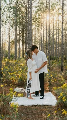 a man and woman kissing in the middle of a forest with yellow wildflowers