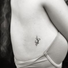 black and white photo of woman's chest with an omastha tattoo on it