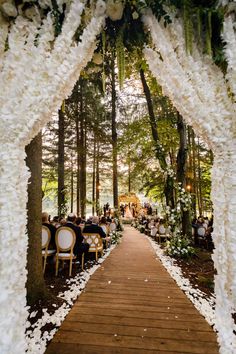 an image of a wedding ceremony with white flowers and greenery on the side of the aisle