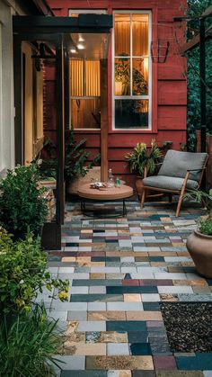 a red house with two chairs and a table on the front porch, surrounded by potted plants