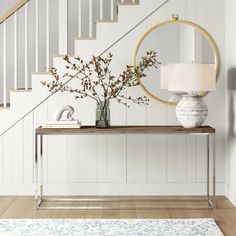 a vase with flowers is sitting on a table in front of a staircase and mirror