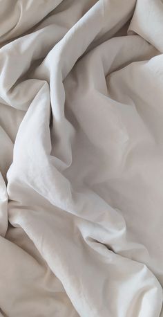 an unmade bed with white sheets and pillows