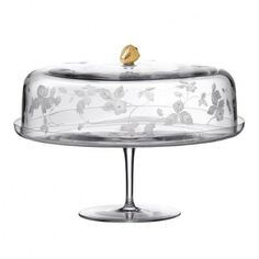 a glass cake dish with a gold bird on top