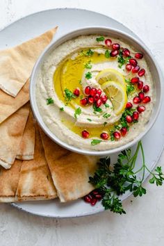 a white plate topped with pita chips and hummus