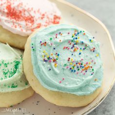 three decorated cookies on a plate with sprinkles