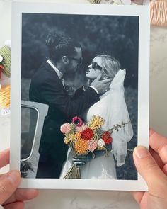 two hands holding up a polaroid with a photo of a bride and groom kissing