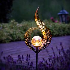 a decorative garden light with purple flowers in the background