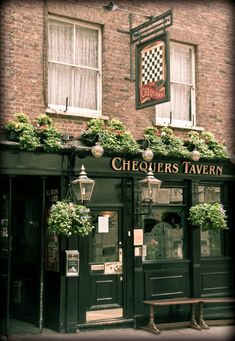 the front of a restaurant with flowers growing on it's windows and an awning