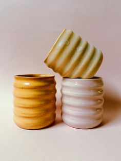 two white and yellow vases sitting next to each other