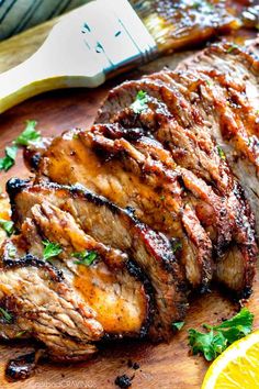 grilled pork chops on a cutting board with lemon wedges and parsley