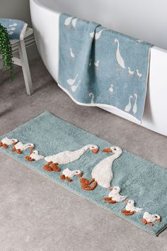 a bath mat with ducks and swans on it next to a tub in a bathroom