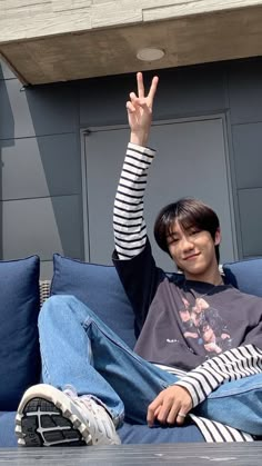 a young man sitting on top of a blue couch with his hand in the air