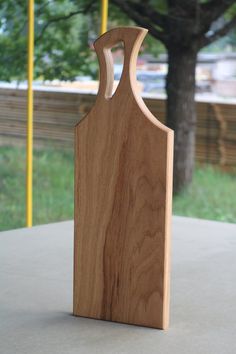 a wooden cutting board sitting on top of a cement table next to a tree in the background