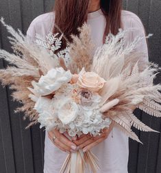 a woman holding a bouquet of flowers and feathers in front of her face with long hair