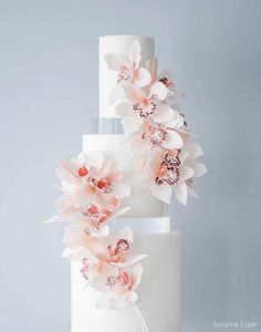 a three tiered white cake with pink flowers on top