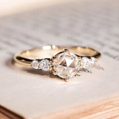 a close up of a ring on top of a piece of paper with an open book in the background