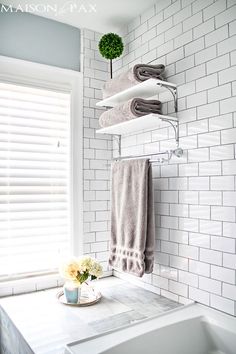 a bathroom with white tile walls and shelves above the bathtub is decorated with flowers