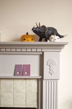 a fireplace mantel with two fake animals on top and one fake pumpkin in the background