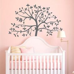 a baby's room with pink walls and a tree decal on the wall