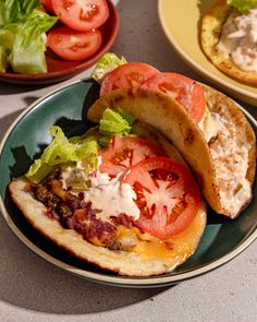 an open faced sandwich with lettuce, tomato and cheese on a green plate