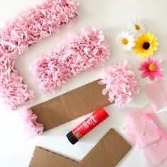 some pink flowers are laying on top of brown paper and other crafting supplies,