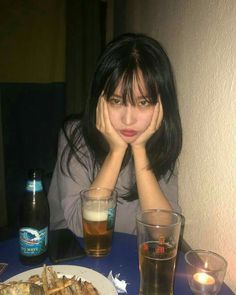 a woman sitting at a table with plates of food and drinks in front of her