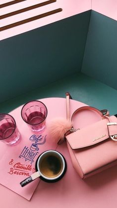 a pink purse sitting on top of a table next to two glasses and a cup