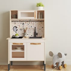 a wooden toy kitchen with an elephant figurine next to it