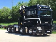 a large black truck parked on top of a dirt road